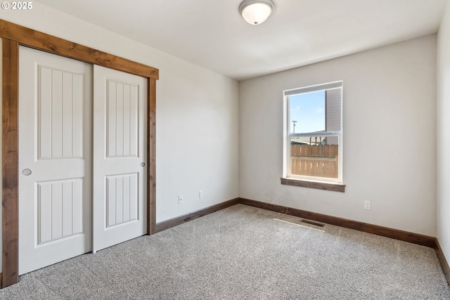 unfurnished bedroom featuring carpet floors, baseboards, and a closet