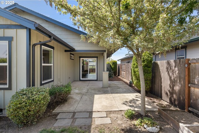 entrance to property with fence, a patio area, and board and batten siding