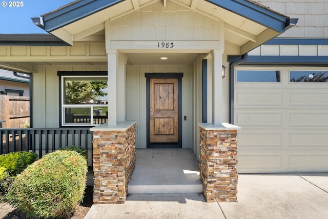 view of exterior entry featuring board and batten siding, a porch, and a garage