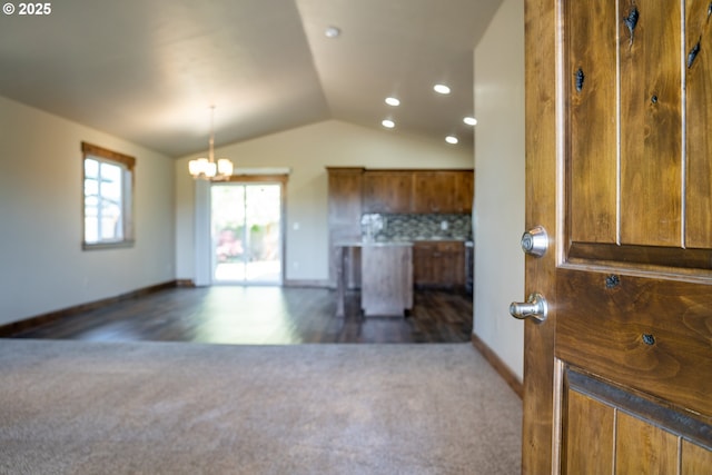 kitchen with dark colored carpet, vaulted ceiling, brown cabinets, baseboards, and recessed lighting