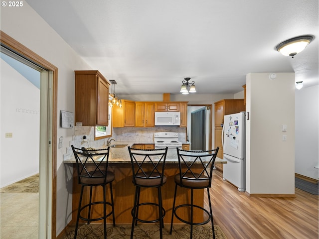 kitchen with sink, backsplash, white appliances, and a breakfast bar