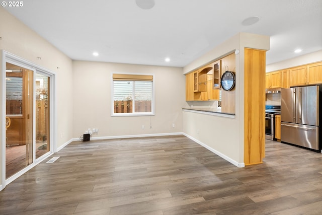 interior space with hardwood / wood-style floors, light brown cabinets, and stainless steel appliances