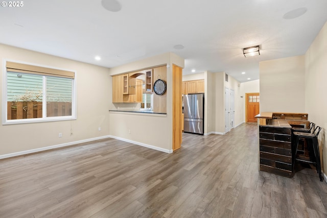 kitchen with light brown cabinetry, hardwood / wood-style floors, and high end fridge