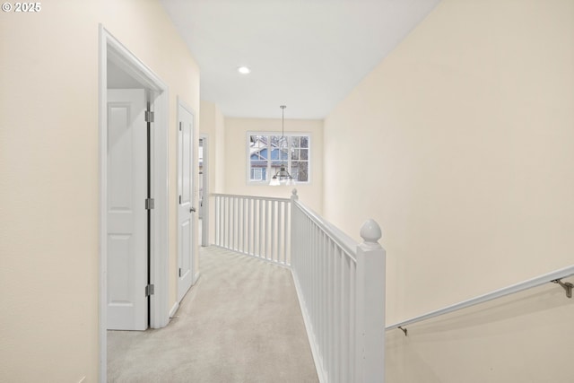 hallway with light carpet and a notable chandelier