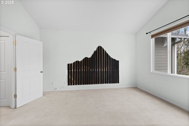 unfurnished room featuring lofted ceiling and light carpet