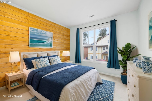 bedroom featuring light carpet and wooden walls