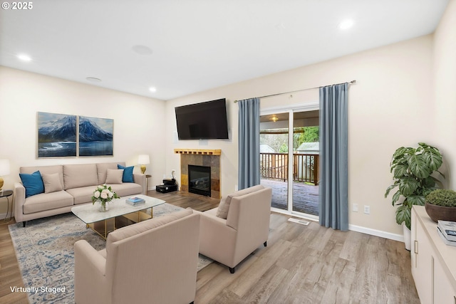 living room with light hardwood / wood-style flooring and a tiled fireplace