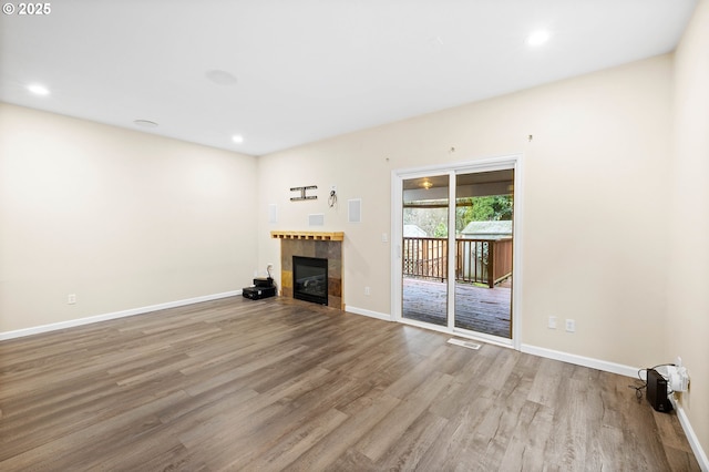 unfurnished living room with light wood-type flooring and a tiled fireplace