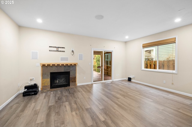 unfurnished living room featuring light wood-type flooring, a wealth of natural light, and a fireplace