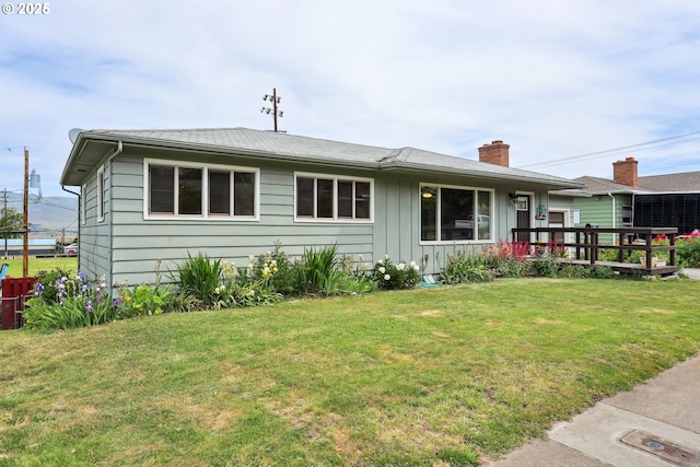 1831 E 14th St, The Dalles, OR 97058 - view of front facade featuring a front lawn, board and batten siding, a deck, and a chimney