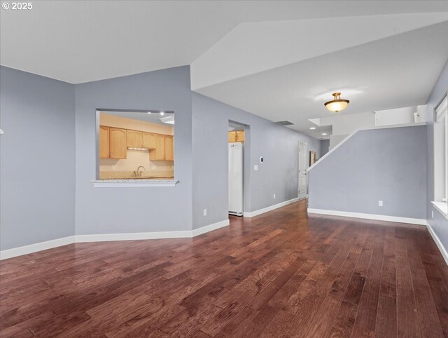 17575 SW Heatherwood Ln, Sherwood, OR 97140 - unfurnished living room with dark wood-style flooring, baseboards, vaulted ceiling, stairway, and a sink