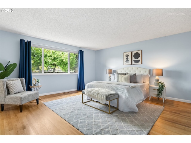 bedroom featuring baseboards, a textured ceiling, and wood finished floors