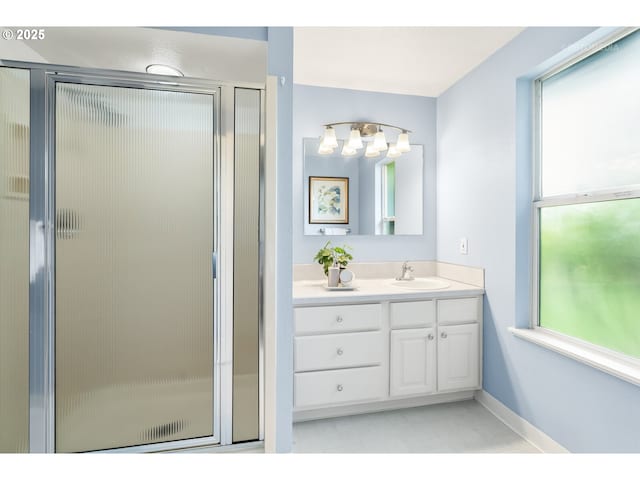 bathroom with baseboards, a shower stall, a healthy amount of sunlight, and vanity