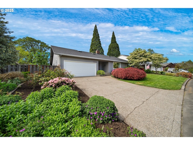 view of front of house with fence, an attached garage, driveway, and a front lawn