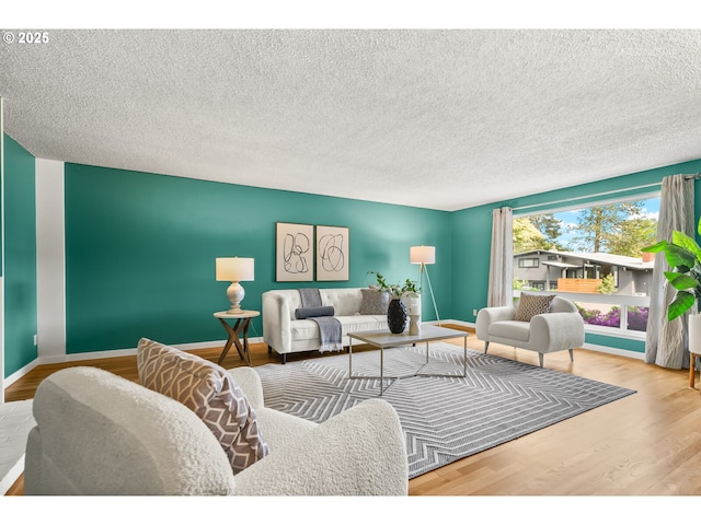 living room with baseboards, a textured ceiling, and wood finished floors