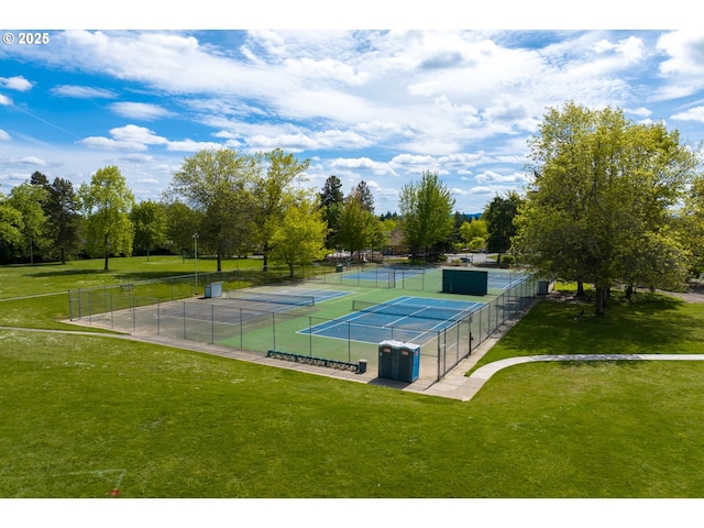 view of tennis court featuring fence and a yard