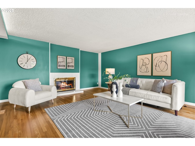 living room featuring baseboards, a glass covered fireplace, and wood finished floors