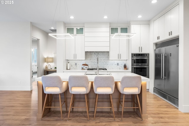 10809 NE 102nd Ave, Vancouver, WA 98662 - kitchen featuring appliances with stainless steel finishes, light countertops, a kitchen island with sink, backsplash, and white cabinetry