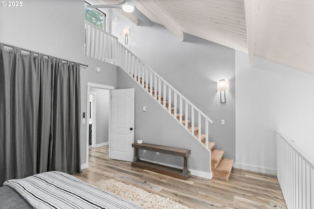 unfurnished bedroom with beam ceiling, baseboards, wood finished floors, and high vaulted ceiling