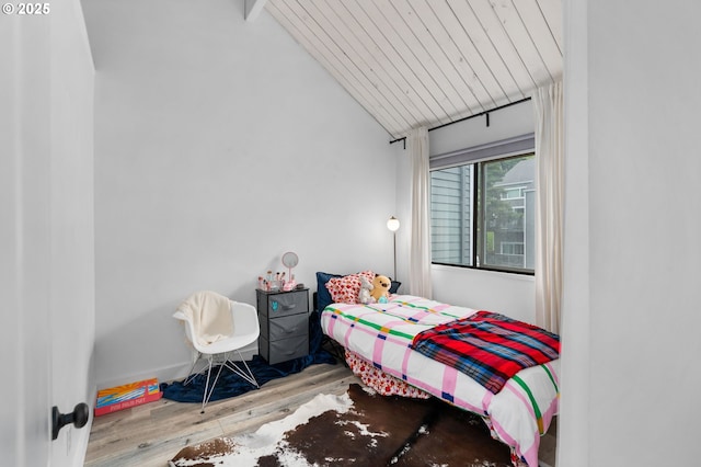 bedroom featuring vaulted ceiling with beams and wood finished floors