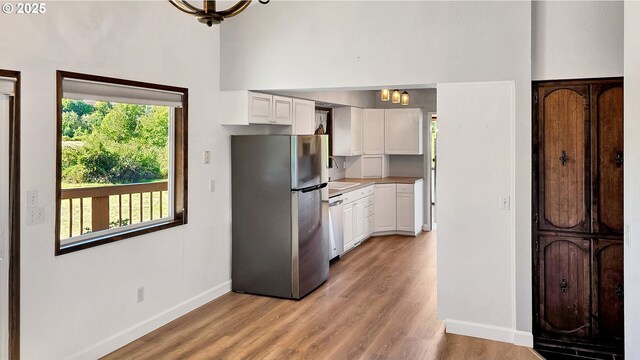 kitchen featuring white cabinetry, light wood finished floors, baseboards, and appliances with stainless steel finishes