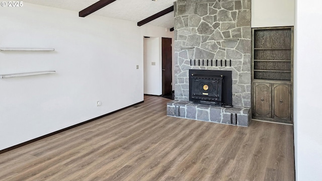 unfurnished living room featuring baseboards, beam ceiling, a textured ceiling, and wood finished floors