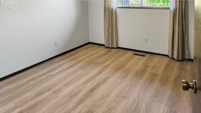 spare room featuring visible vents, baseboards, and wood finished floors