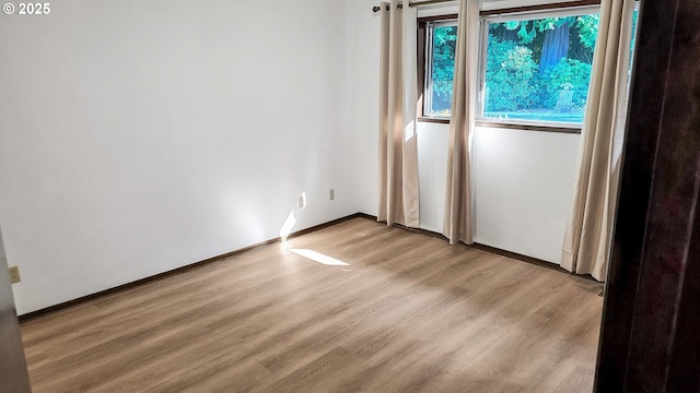 unfurnished room featuring baseboards and light wood-style floors