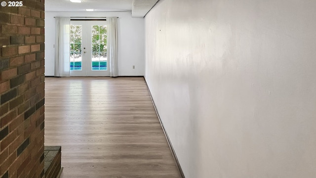 spare room featuring wood finished floors, french doors, and baseboards