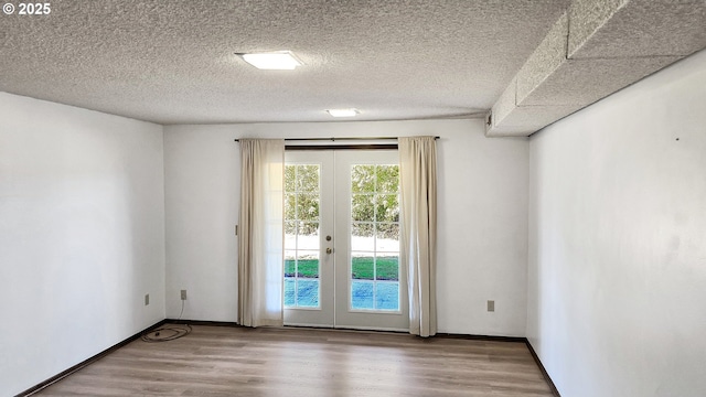 unfurnished room featuring french doors, baseboards, a textured ceiling, and wood finished floors