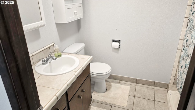 full bath featuring tile patterned flooring, toilet, a shower with shower curtain, a textured wall, and vanity