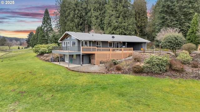 rear view of property featuring a patio, a lawn, a deck, and a chimney