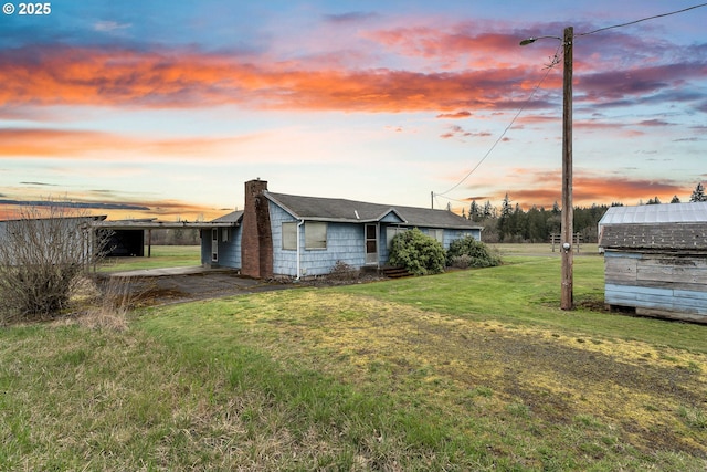 exterior space featuring an outbuilding, a lawn, and a chimney