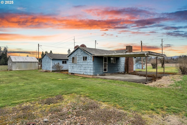 rear view of house with a yard, an outbuilding, a storage shed, and a chimney