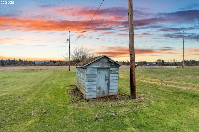 outdoor structure at dusk with an outdoor structure, a yard, a rural view, and a storage unit