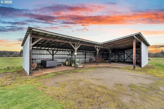 outdoor structure at dusk featuring a detached carport, an outdoor structure, and a pole building