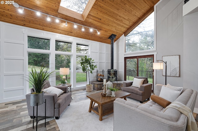19434 S Logan Dr, Beavercreek, OR 97004 - living area featuring track lighting, a wood stove, wood ceiling, a skylight, and light wood-style floors