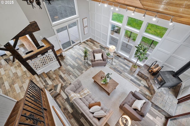 19434 S Logan Dr, Beavercreek, OR 97004 - living room featuring rail lighting, a decorative wall, a wood stove, wood finished floors, and wooden ceiling