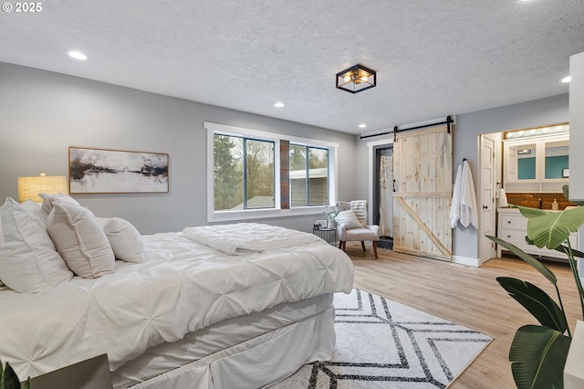 19434 S Logan Dr, Beavercreek, OR 97004 - bedroom with a barn door, recessed lighting, light wood finished floors, a textured ceiling, and ensuite bathroom