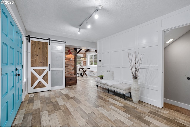 19434 S Logan Dr, Beavercreek, OR 97004 - sitting room with a barn door, light wood-style flooring, a textured ceiling, and a decorative wall