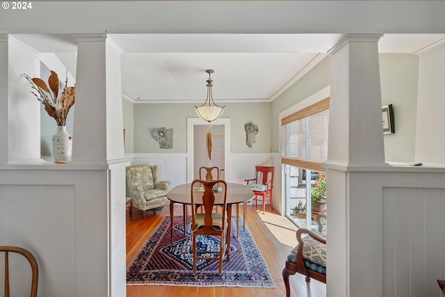 living area featuring a wainscoted wall, wood finished floors, and ornamental molding