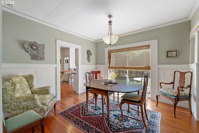 dining area featuring a wainscoted wall, ornamental molding, wood finished floors, and plenty of natural light