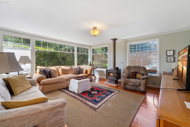 living area with wood finished floors, crown molding, baseboards, and a wood stove
