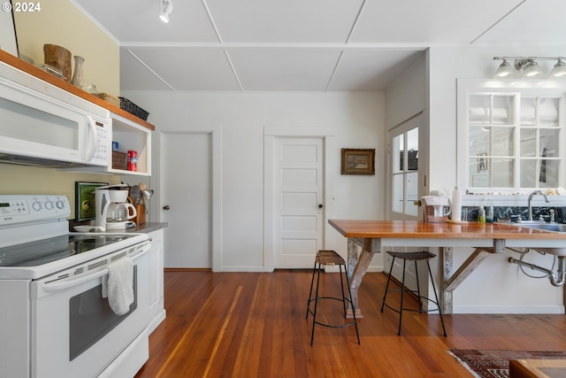 kitchen with baseboards, dark wood finished floors, a sink, and white appliances