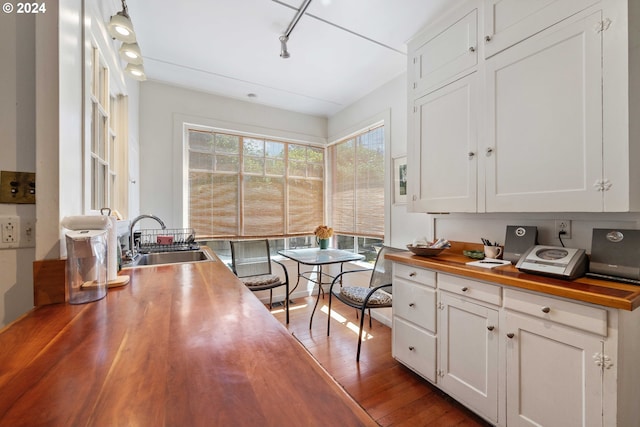 kitchen featuring a sink, white cabinetry, wood finished floors, wood counters, and track lighting