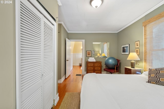 bedroom featuring light wood-style flooring, crown molding, a closet, and baseboards