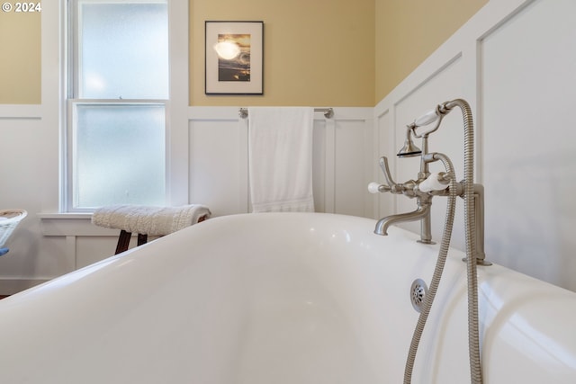 bathroom featuring a wainscoted wall, a decorative wall, and a freestanding bath