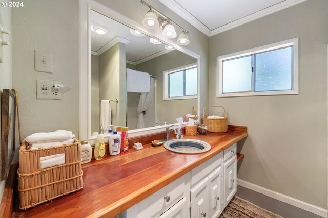bathroom featuring vanity, a shower with shower curtain, crown molding, and baseboards