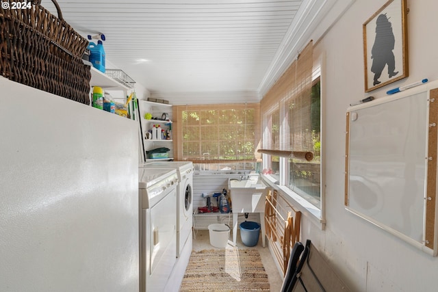 washroom featuring washer and clothes dryer, crown molding, laundry area, and a sink