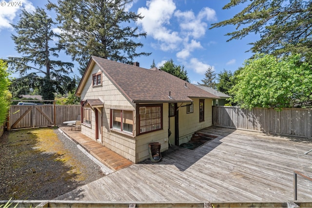 exterior space with roof with shingles, fence, and a deck